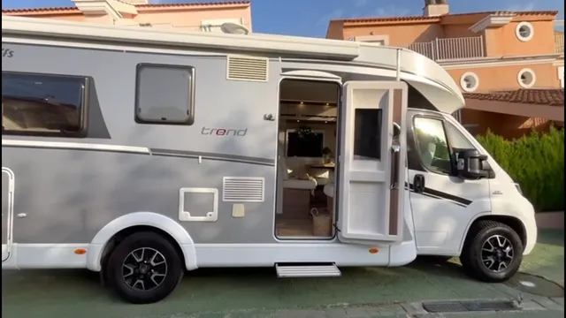 Lateral de la autocaravana con la puerta abierta y el salón visible al fondo