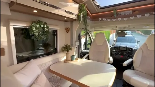Comedor con banco tapizado y mesa junto a los asientos de cabina, bajo una claraboya